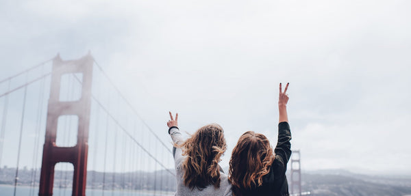 Two young women standing in front of the Golden Gate Bridge.