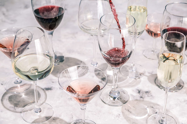 Image of wine glasses filled with reds, whites, and rosés.