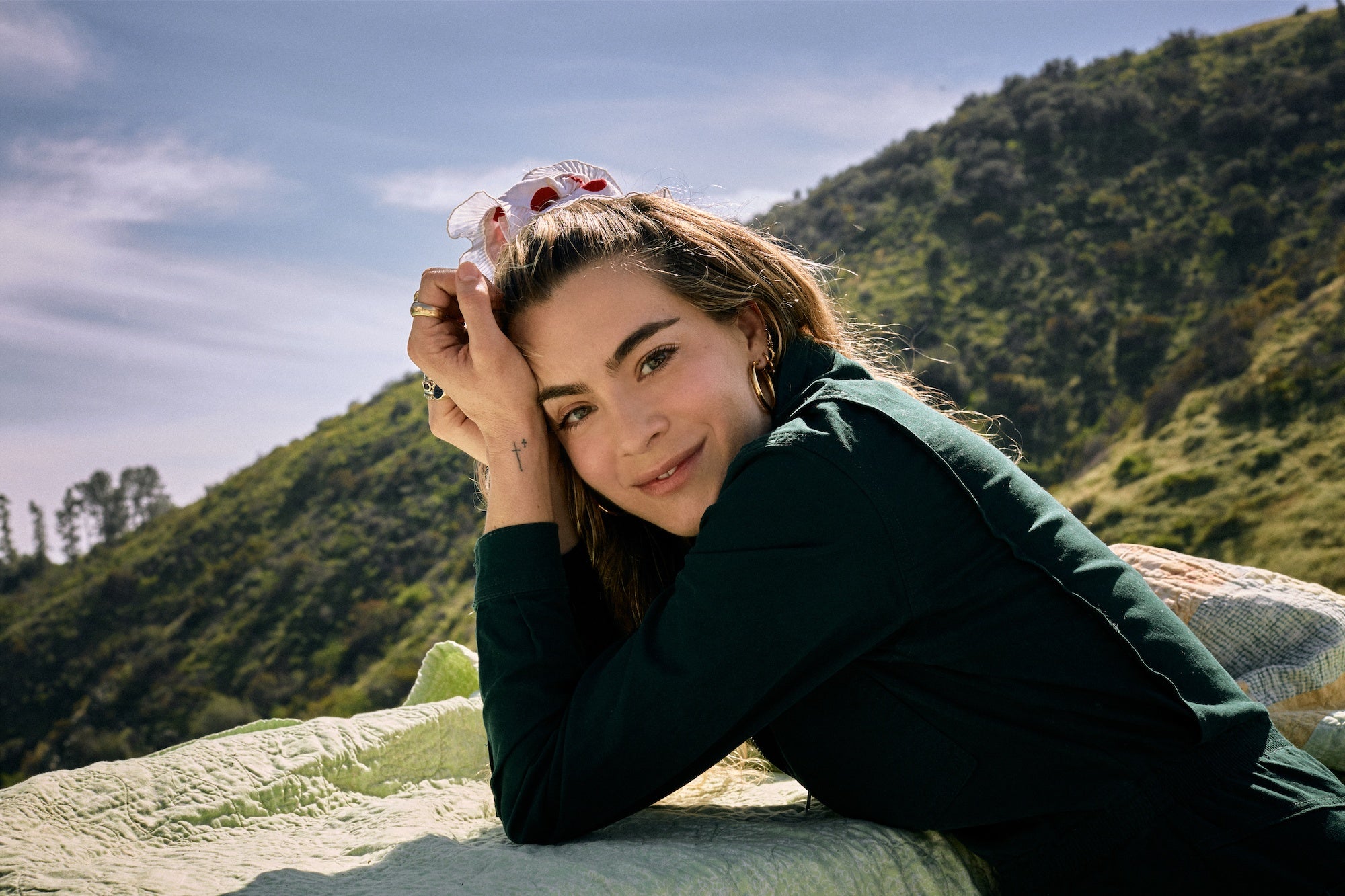 Chelsea Leyland leaning on a balcony, overlooking a green hill
