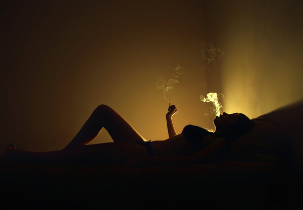 Image of women's silhouette smoking in bed.